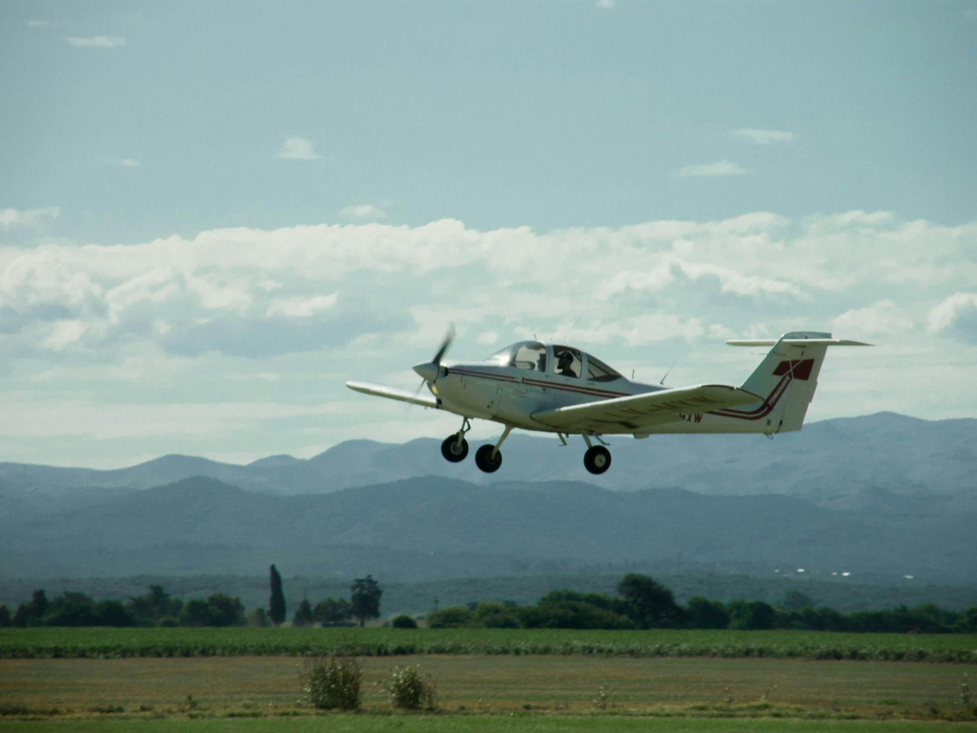 green and yellow fighter plane flying over green grass field during daytime